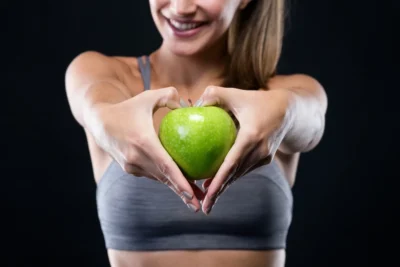 donna con pelle del viso e fegato sani tiene una mela verde in mano